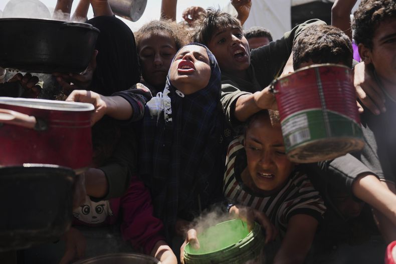 Palestinos tratan de obtener alimentos donados en una cocina comunitaria en Jan Yunis, Franja de Gaza, el 5 de mayo de 2025. (AP Foto/Abdel Kareem Hana)