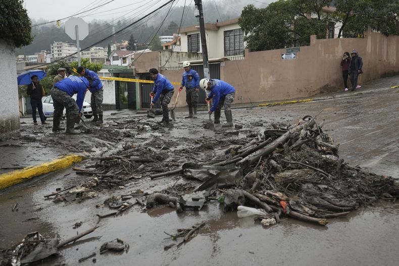 Agentes de policía despejan una calle después de la caída de un aluvión de agua, lodo y palos a través del sector de La Gasca en Quito, Ecuador, el martes 2 de abril de 2024. (AP Foto/Dolores Ochoa)