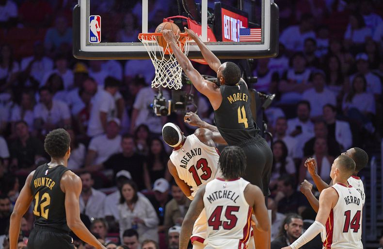 Evan Mobley (4) de los Cavaliers de Cleveland clava al balón ante Bam Adebayo del Heat de Miami en los playoffs de la NBA, el sábado 26 de abril de 2025, en 2025, en Miami. (AP Foto/Michael Laughlin)