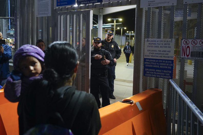 Paula, en primer plano, de Guatemala, sostiene a su hija mientras les pregunta a agentes de la Oficina de Aduanas y Protección Fronteriza de Estados Unidos acerca de las nuevas normas para el asilo, en el Puerto de Entrada de San Ysidro, el jueves 11 de mayo de 2023, en Tijuana, México. Migrantes centroamericanos podrán tramitar sus solicitudes desde Guatemala en los Centros de Movilidad Segura que financia el gobierno estadounidense y que se implementarán en países como Guatemala, usados como tránsito de migrantes, informó un funcionario del gobierno guatemalteco el viernes 9 de junio de 2023. (AP Foto/Gregory Bull)