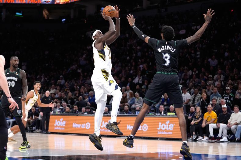 Pascal Siakam, delantero de los Pacers de Indiana, al centro, sube para lanzar sobre Jaden McDaniels (3), delantero de los Timberwolves de Minnesota, durante la primera mitad de un juego de baloncesto de la NBA, el domingo 26 de octubre de 2025, en Mineápolis. (AP Photo/Abbie Parr)
