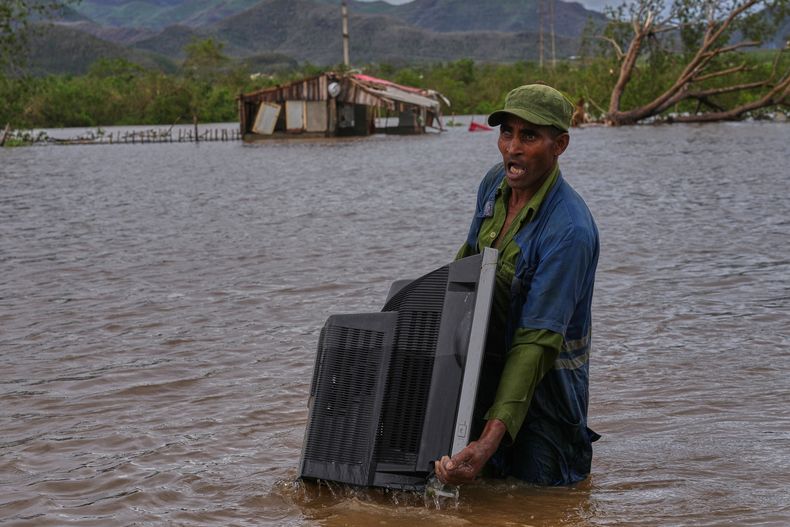 Un hombre traslada un televisor desde su casa inundada por el huracán Melissa en Santiago de Cuba, el miércoles 29 de octubre de 2025. (AP Foto/Ramón Espinosa)