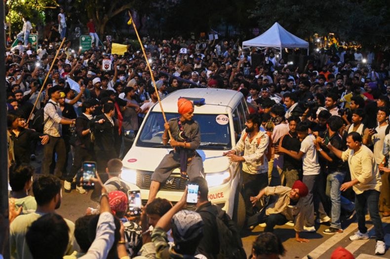 Un manifestante, sentado sobre un auto policial durante una manifestación para reclamar reformas educativas como parte de la protesta del movimiento del Partido de las Cucarachas en Nueva Delhi, India, el 22 de julio de 2026. (AP Foto/Vipin)