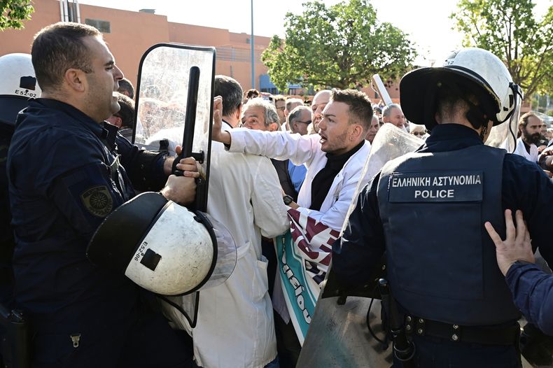 Personal médico se enfrenta a la policía antidisturbios después de reunirse para protestar por el estado de los servicios de salud pública durante una visita al hospital del primer ministro en Atenas, Grecia, el miércoles 15 de octubre de 2025. (Michalis Karayiannis/Eurokinissi vía AP)