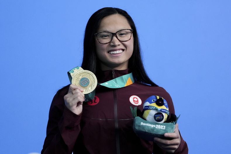 La canadiense Maggie McNeil posa con su medalla de oro tras ganar los 100 metros mariposa en la natación de los Juegos Panamericanos en Santiago, Chile, el 22 de octubre de 2023. (AP Foto/Silvia Izquierdo)