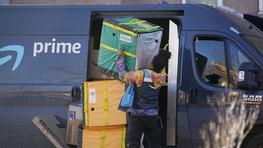 Una persona que entrega mercancía de Amazon Prime acomoda paquetes al hacer una parada en un edificio de apartamentos, el martes 28 de noviembre de 2023, en Denver. (AP Foto/David Zalubowski)