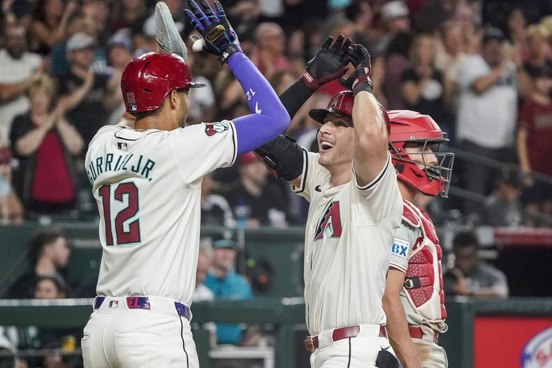 Jake McCarthy de los Diamondbacks de Arizona le da los cinco al cubano Lourdes Gurriel Jr. tras su jonrón en la quinta entrada ante los Filis de Filadelfia el sábado 10 de agosto del 2024. (AP Foto/Darryl Webb)