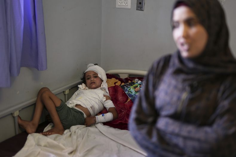 Iman Abu Shabab, de 30 años, acompaña a su hijo de 7 años, Hamza, quien se recupera en cama de quemaduras de tercer grado que sufrió cuando, aterrado por un bombardeo israelí, derramó un plato caliente de arroz y lentejas en la casa de campaña de su familia en el sur de Gaza el mes pasado, en el hospital Nasser en Jan Yunis, Franja de Gaza, el domingo 4 de mayo de 2025.(AP Foto/Abdel Kareem Hana)
