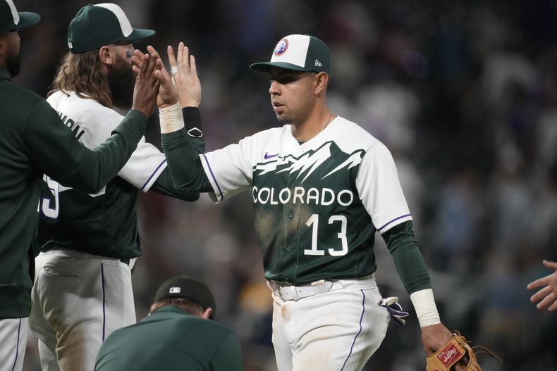 El mexicano Alan Trejo, de los Rockies de Colorado, recibe la felicitación de sus compañeros, tras el encuentro ante los Cerveceros de Milwaukee, el miércoles 3 de mayo de 2023 (AP Foto/David Zalubowski)