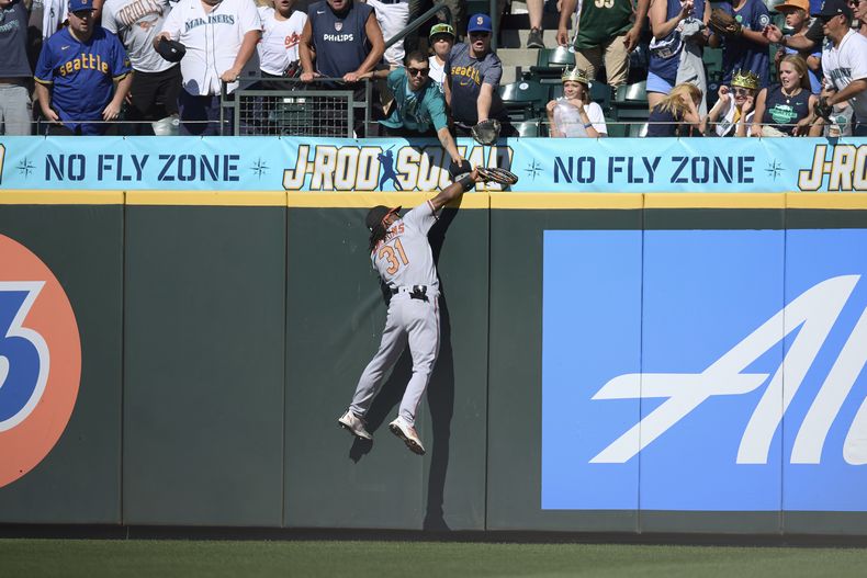 El jardinero central de los Orioles de Baltimore, Cedric Mullins, atrapa una pelota bateada por Ty France, de los Marineros de Seattle, por encima de la barda durante la novena entrada del juego de béisbol, el domingo 13 de agosto de 2023, en Seattle. (AP Foto/John Froschauer)