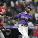 El venezolano Harold Castro, de los Rockies de Colorado, conecta un doble de dos anotaciones en la séptima entrada del partido contra los Rojos de Cincinnati en Denver, el lunes 15 de mayo de 2023. A la izquierda, el receptor de los Rojos, Tyler Stephenson. (AP Foto/David Zalubowski)