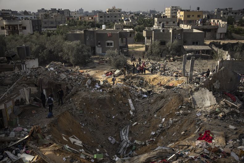 Palestinos revisan un sitio luego de que fue impactado por un bombardeo israelí en Rafah, Franja de Gaza, el martes 12 de diciembre de 2023. (AP Foto/Fatima Shbair)