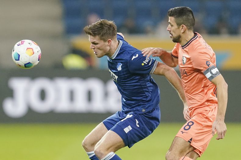 Marius Bülter, a la izquierda, de Hoffenheim, disputa el balón con Anthony Losilla, del Bochum, durante el partido del viernes 8 de diciembre de 2023, en Sinsheim, Alemania. (Uwe Anspach/dpa via AP)