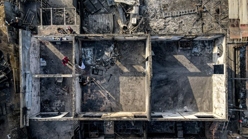 Un grupo de personas realiza labores de limpieza en medio de escombros en sus viviendas consumidas por las llamas de un incendio forestal en Viña del Mar, Chile, el lunes 5 de febrero de 2024. (AP Foto/Esteban Félix)