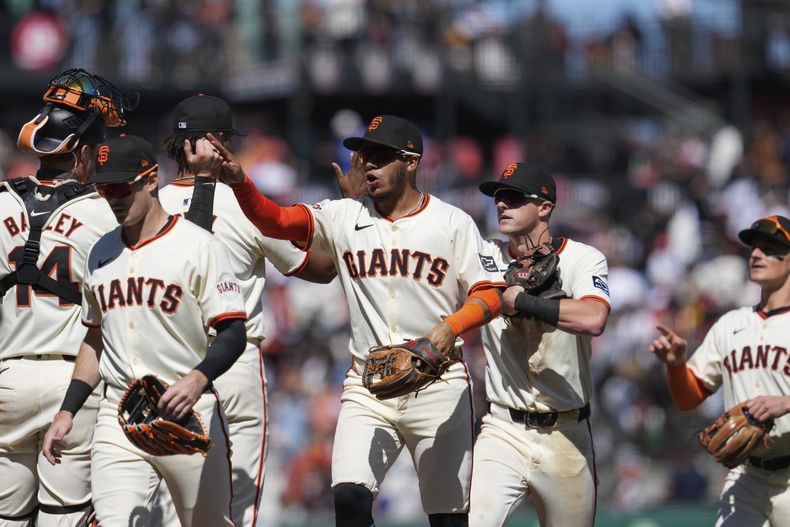 Thairo Estrada, centro, de los Gigantes de San Francisco, celebra con Patrick Bailey, a la izquierda, después de la victoria del equipo sobre los Piratas de Pittsburgh en un partido de béisbol, el domingo 28 de abril de 2024, en San Francisco. (AP Foto/Godofredo A. Vásquez)