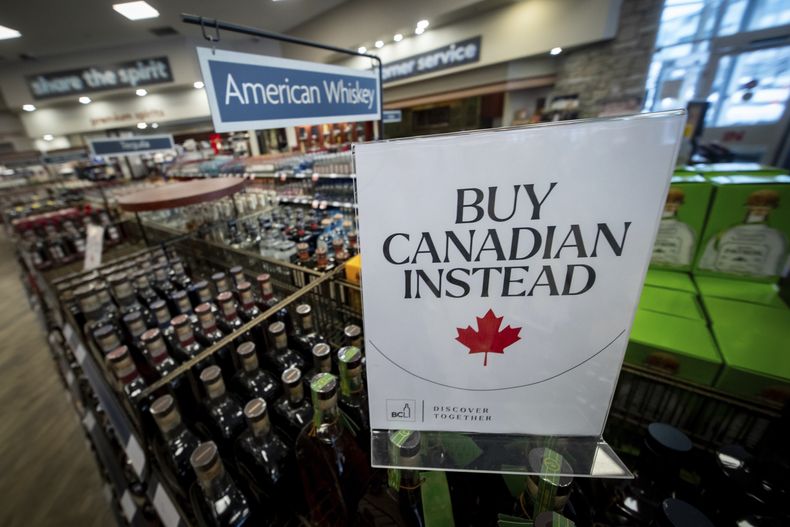 Un letrero frente a la sección de whisky estadounidense en una licorería de Columbia Británica, Canadá, recomienda comprar productos nacionales, en Vancouver, el 2 de febrero de 2025. (Ethan Cairns/The Canadian Press vía AP)