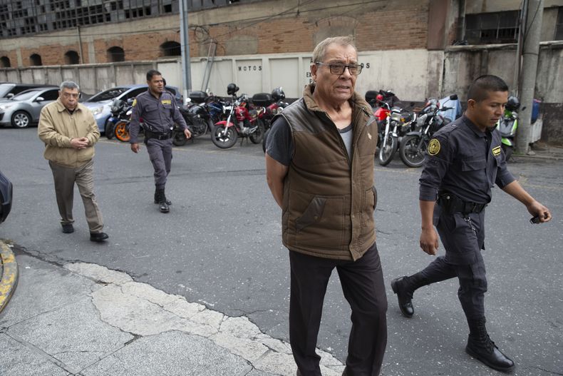 ARCHIVO - Los excomandantes del ejército guatemalteco Benedicto Lucas García, al frente, y Manuel Callejas, en el extremo izquierdo, son escoltados a la corte esposados en la Ciudad de Guatemala, el 25 de noviembre de 2019, donde enfrentan cargos de dirigir una campaña militar contra las comunidades mayas ixiles entre 1978 y 1982 durante la guerra civil del país. (AP Foto/Moisés Castillo, Archivo)