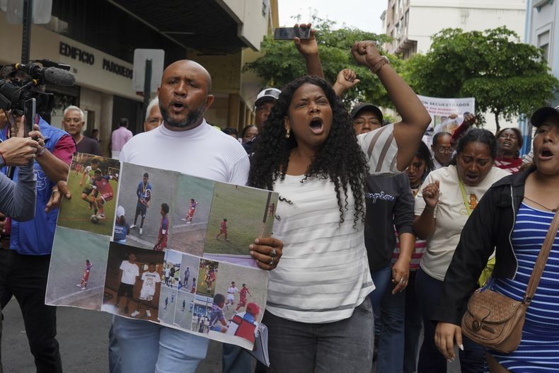 Luis Arroyo, a la izquierda, con las fotos de sus dos hijos desaparecidos, Ismael y Josué, quienes fueron vistos por última vez el pasado 8 de diciembre, tras intentar huir de un convoy militar junto a otros dos jóvenes, durante una protesta con su familia y organizaciones ante la sede de la fiscalía en Guayaquil, el lunes 23 de diciembre de 2024. (AP Foto/César Muñoz)
