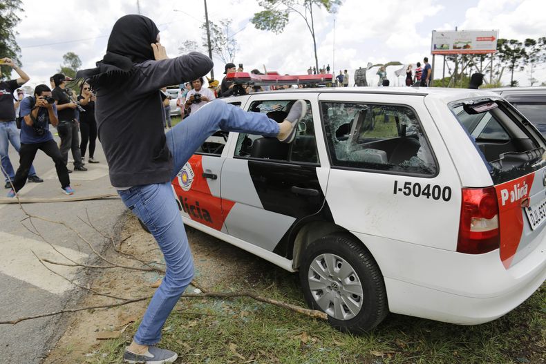 Un manifestante enmascarado golpea un veh&iacute;culo policial vac&iacute;o cerca del laboratorio Instituto Royal en protesta por la prueba de drogas con animales en Sao Roque, Brasil, el s&aacute;bado, 19 de octubre del 2013. (Foto AP/Nelson Antoine)