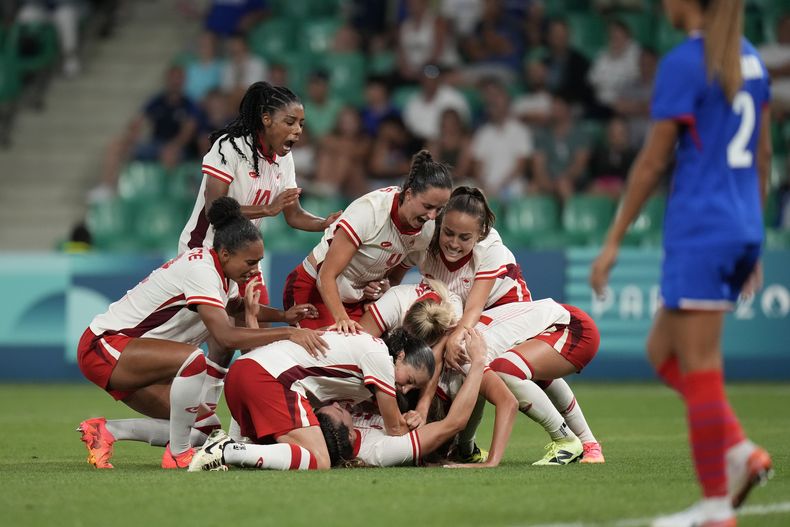 Las jugadoras de Canadá celebran después de que Vanessa Gille, abajo en el centro, anotó el segundo gol de su equipo durante el partido de fútbol femenino del Grupo A entre Canadá y Francia en el Estadio Geoffroy-Guichard durante los Juegos Olímpicos de Verano de 2024, el domingo 28 de julio de 2024, en Saint-Etienne, Francia. (AP Foto/Silvia Izquierdo)