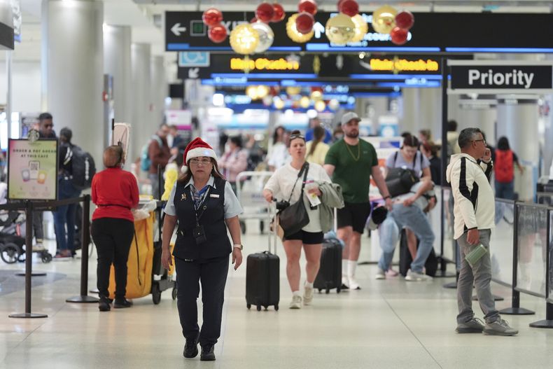 Una empleada de American Airlines con un gorro de Santa Claus camina por el Aeropuerto Internacional de Miami, el 24 de diciembre de 2024, en Miami. (AP Foto/Rebecca Blackwell)