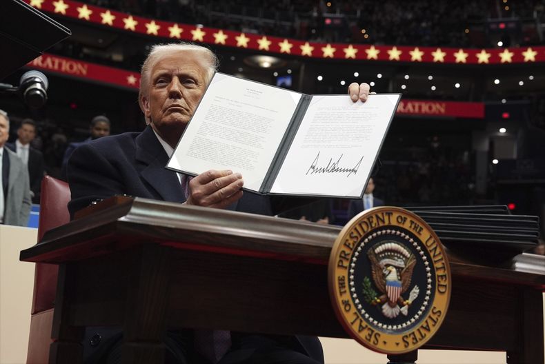 El presidente Donald Trump firma una orden ejecutiva durante un desfile bajo techo por la inauguración presidencial en el estadio Capital One, el lunes 20 de enero de 2025, en Washington. (AP Foto/Evan Vucci)