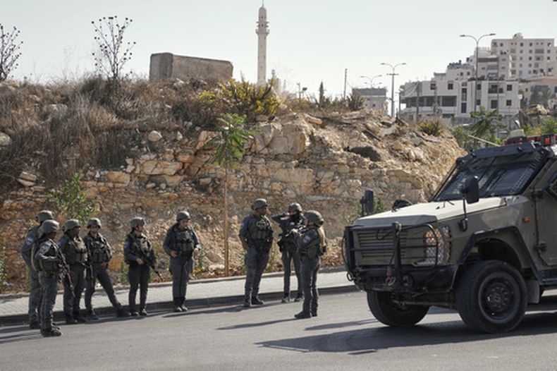 Soldados israelíes se reúnen en el lugar de un ataque a tiros perpetrado por hombres armados palestinos en un cruce cerca de Hebrón, en la Cisjordania ocupada, el viernes 23 de octubre de 2026. (Foto AP/Mahmoud Illean)