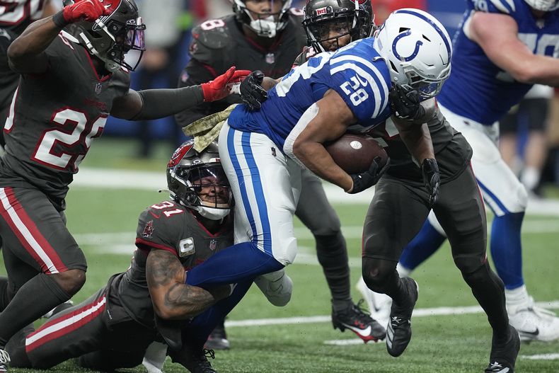 Antoine Winfield Jr. (31), safety de los Buccaneers de Tampa Bay, derriba a Jonathan Taylor (28), running back de los Colts de Indianápolis, durante la segunda mitad del juego de la NBA, el domingo 26 de noviembre de 2023, en Indianápolis. (AP Foto/Darron Cummings)