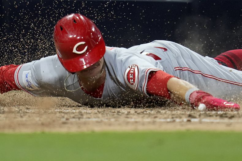 TJ Friedl, de los Rojos de Cincinnati, se desliza para anotar en el octavo inning del juego ante los Padres de San Diego, el martes 2 de mayo de 2023 (AP Foto/Gregory Bull)
