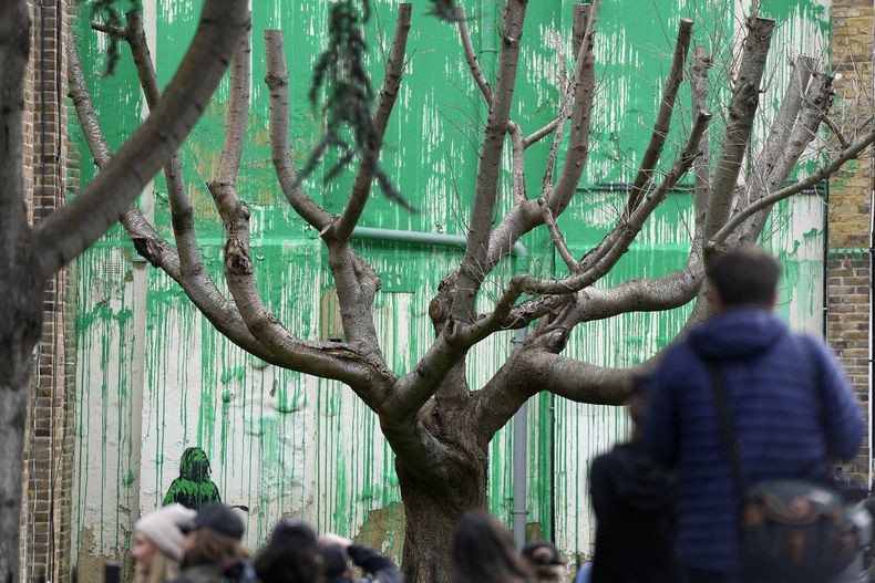 Personas miran un nuevo mural de Banksy en una pared en Londres, el lunes 18 de marzo de 2024. Un nuevo mural de Banksy en el vecindario de Finsbury Park atrajo multitudes a una calle de Londres el lunes, incluso antes de que el esquivo artista de graffiti confirmara que la obra era suya. (Foto AP/Alastair Grant)