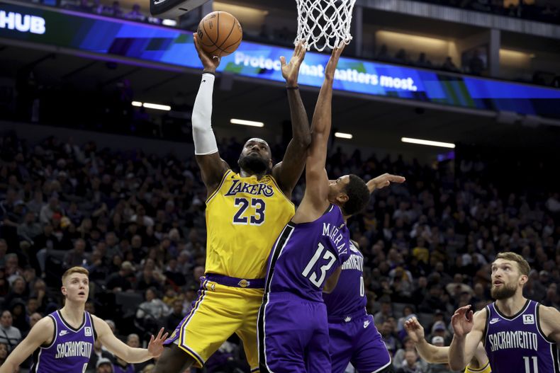 El alero de los Lakers de Los Ángeles LeBron James lanza el balón sobre el alero de los Kings de Sacramento Keegan Murray el jueves 19 de diciembre del 2024. (AP Foto/Jed Jacobsohn)