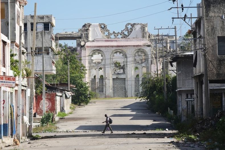Un hombre pasa por una calle desierta donde se ve parte de una catedral destruida por un terremoto en el centro de Puerto Príncipe, Haití, el lunes 16 de marzo de 2026. (AP Foto/Odelyn Joseph)