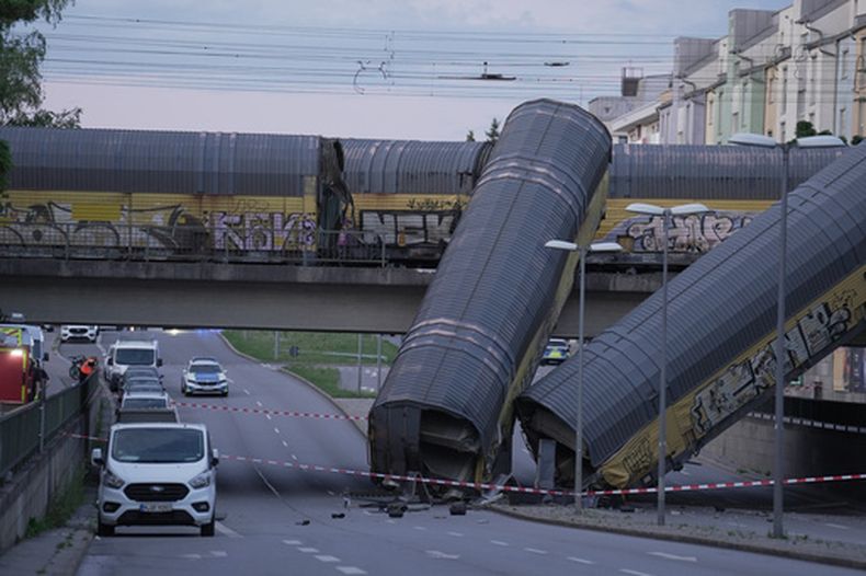 Dos vagones de un tren de mercancías, caídos sobre una carretera tras caer de un puente en Múnich, Alemania, el 20 de junio de 2026. (Ehsan Monajati/dpa via AP)