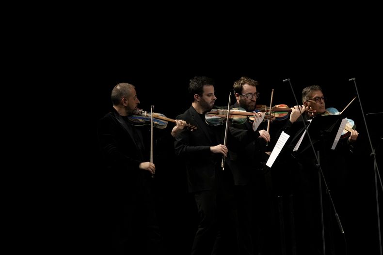 Integrantes de la Orquesta del Mar tocan violines hechos con madera de barcos de inmigrantes en Milán, en el norte de Italia el sábado 10 de febrero de 2024. Reclusos de la prisión Opera de máxima seguridad usan la madera de los botes de inmigrantes para crear instrumentos musicales que la Orquesta del Mar tocó en su debut en el Teatro alla Scala (Foto AP/Antonio Calanni)
