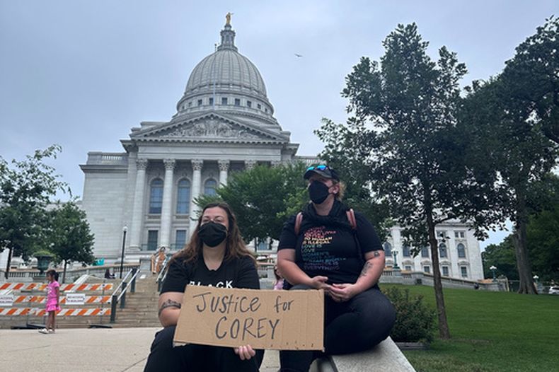 Lilly Nimmer y Reba Bergmann sostienen un cartel en protesta por el tiroteo policial de Corey Ruiz frente al Capitolio estatal de Wisconsin, el 25 de julio de 2026, en Madison, (Foto AP/Scott Bauer)