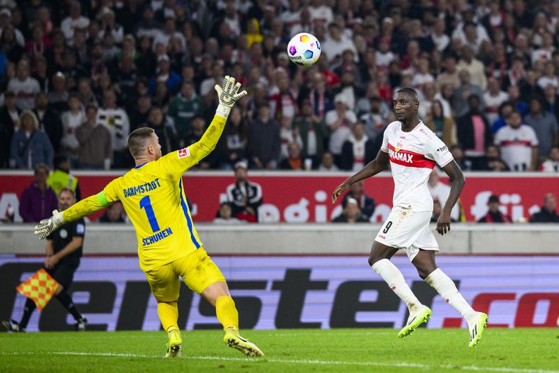 Serhou Guirassy, derecha, de Stuttgart, anota el tercer gol de su equipo en contra del portero de Darmstadt, Marcel Schuhen, durante el partido de fútbol de la Bundesliga de Alemania entre Darmstadt 98 y VfB Stuttgart, en Stuttgart, Alemania, el viernes 22 de septiembre de 2023. (Tom Weller/dpa vía AP)