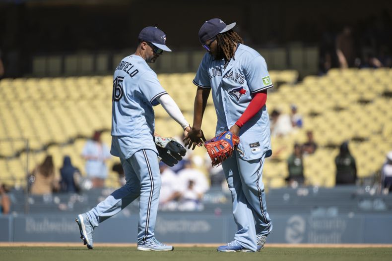 Whit Merrifield (izquierda) y el dominicano Vladimir Guerrero Jr., de los Azulejos de Toronto, festejan la victoria sobre los Dodgers de Los Ángeles, el miércoles 26 de julio de 2023 (AP Foto/Kyusung Gong)