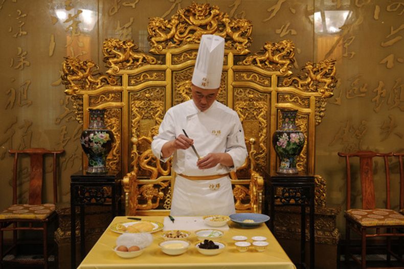 El chef Fan Liangliang demuestra la preparación de un platillo en el restaurante Fangshan, en el Parque Beihai en Beijing, el 23 de julio de 2026. (AP Foto/Andy Wong)