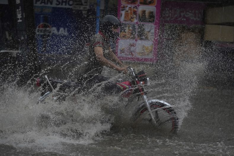 Un motociclista circula por una avenida inundada por las fuertes lluvias monzónicas en Lahore, Pakistán, el domingo 3 de agosto de 2025. (AP Foto/K.M. Chaudary)