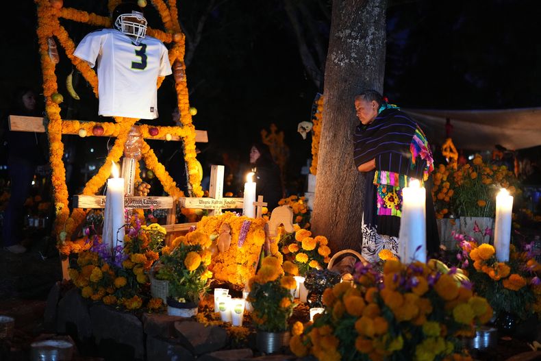Una mujer a un costado de la tumba de un ser querido durante las celebraciones del Día de Muertos, el viernes 31 de octubre de 2025, en el cementerio de Tzintzuntzan, en el estado de Michoacán, México. (AP Foto/Eduardo Verdugo)