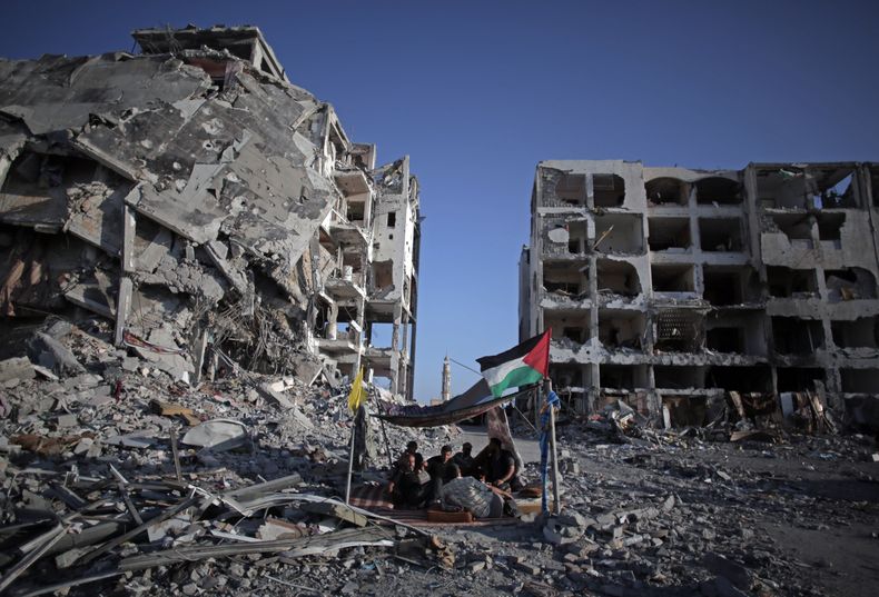 El palestino Ziad Rizk, de 38 a&ntilde;os, aparece sentado con otros en un peque&ntilde;o refugio junto a las destruidas torres Nada, en el pueblo de Beit Lahiya, en el norte de la Franja de Gaza, el lunes, 11 de agosto de 2014. (AP Photo/Khalil Hamra)