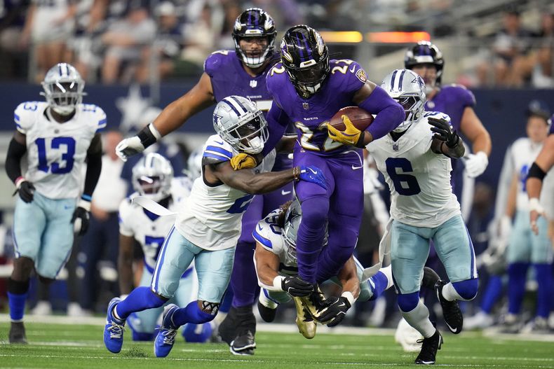 Derrick Henry (22), running back de los Ravens de Baltimore, corre mientras Jourdan Lewis (2), Eric Kendricks, abajo, y Donovan Wilson (6), defensivos de los Cowboys de Dallas, intentan detenerlo en la primera mitad del juego de la NFL, el domingo 22 de septiembre de 2024, en Arlington Texas. (AP Foto/Julio Cortez)