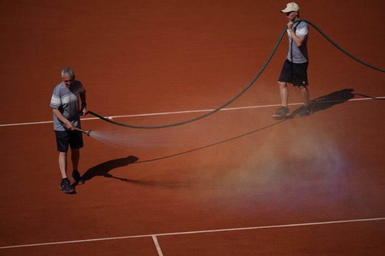 Trabajadores del estadio rocían la cancha con agua durante el partido de primera ronda de individuales femeninos entre las estadounidenses Coco Gauff y Taylor Townsend en el torneo de tenis de Roland Garros en París, el martes 26 de mayo de 2026. (Foto AP/Christophe Ena)
