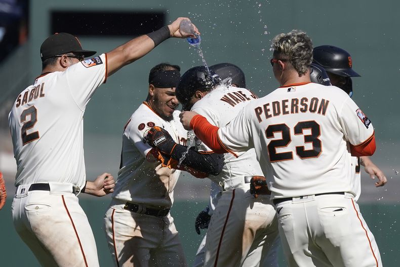 LaMonte Wade Jr. es felicitado por sus compañeros de los Gigantes de San Francisco, luego de conectar un elevado que significó el triunfo ante los Guardianes de Cleveland, el miércoles 13 de septiembre de 2023 (AP Foto/Jeff Chiu)