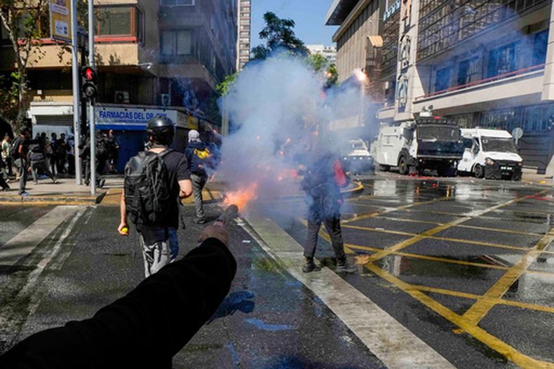 Un joven dispara un arma casera contra la policía durante una protesta estudiantil contra la propuesta del gobierno de reducir el presupuesto de educación y contra el aumento del precio de la gasolina en Santiago de Chile, el jueves 26 de marzo de 2026. (Foto AP/Esteban Félix)