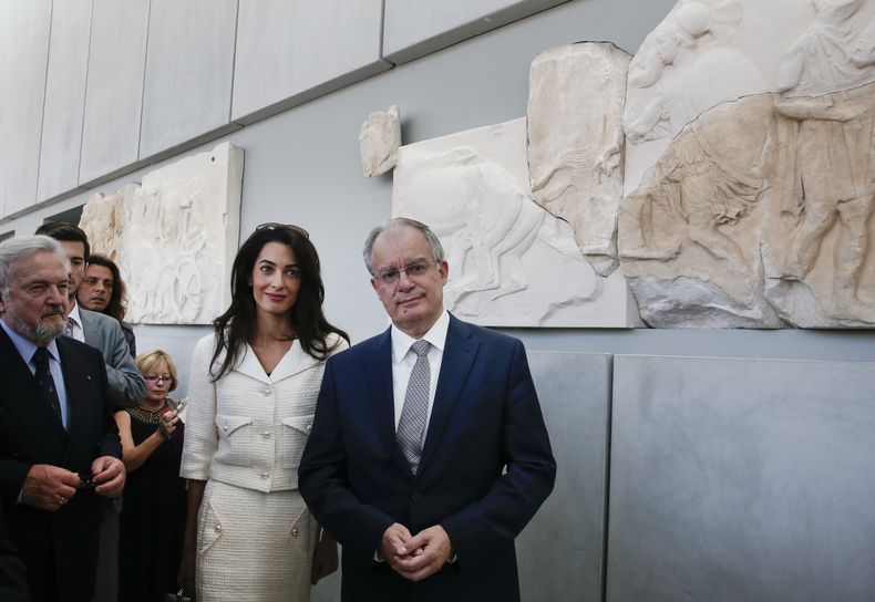 ARCHIVO – La abogada Amal Clooney y el ministro de Cultura y Deportes de Grecia, Konstantinos Tasoulas, derecha, visitan el museo de la Acrópolis en Atenas, el miércoles 15 de octubre de 2014. (AP Foto/Yorgos Karahalis, Archivo)