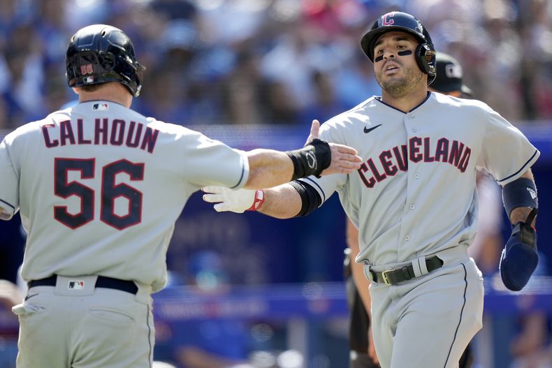 El dominicano Ramón Laureano es felicitado por su compañero Kole Calhoun (56) luego de impulsar una carrera para los Guardianens de Cleveland en la octava entrada del juego ante los Azulejos de Toronto, en Toronto. Domingo 27 de agosto de 2023. (Frank Gunn/The Canadian Press via AP)