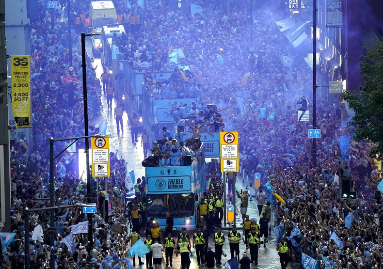 Jugadores del Manchester City recorren las calles de la ciudad en autobús descapotable para festejar con la afición tras ganar la tripleta de títulos el lunes 12 de junio del 2023. (Danny Lawson/PA via AP)