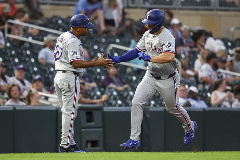 Wyatt Langford de los Rangers de Texas celebra su jonrón en la octava entrada con el entrenador de tercera base Tony Beasley en el encuentro ante los Mellizos de Minnesota el martes 10 de junio del 2025. (AP Foto/Matt Krohn)