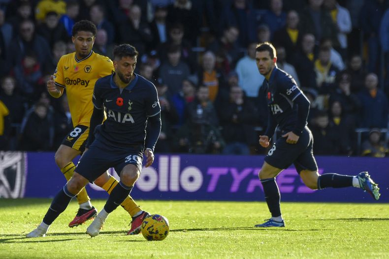 El volante de Tottenham Rodrigo Bentancur (primer plano) avanza con el balón frente a Joao Gomes de Wolverhampton durante un partido de la Liga Premier, el sábado 11 de noviembre de 2023. (AP Foto/Rui Vieira)